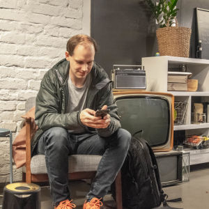 Peter Sunde Kolmisoppi drack hellre te än kaffe när han skulle intervjuas av Yle Vega. Peter Sunde Kolmisoppi petar på sin mobiltelefon i en fåtölj i Parads väntrum bredvid en gammal tv.