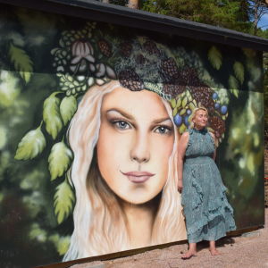 kvinna framför konstverk på husvägg