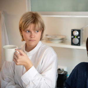 Kaksi nuorta naista viettävät aikaa kimppakämpän keittiössä radiota kuunnellen.