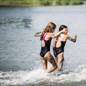 Tre barn springer i vattnet.