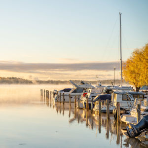 Båtar vid en båthamn en höstmorgon, på havet syns lite dimma som stiger upp.