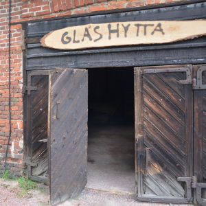 Glashyttan finns i gamla tackjärnsgjuteriet som ägs av Bruksmuseet. Nästa sommar ska det finnas ännu mera konst i huset, lovar Hohenthal. Gamla trädörrar med texten glashytta ovanför.
