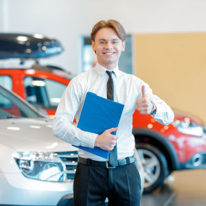 Autokauppias nostaa peukkua autojen edessä