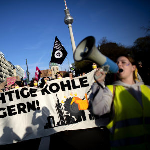 Folkmassa som håller i en banderoll, en kvinna skriker i en megafon.
