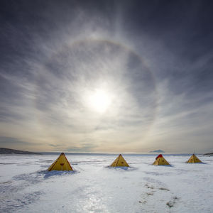 En låg sol över tält på isen i Antarktis. 