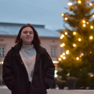 Emilie Jäntti, ordförande för Finlands Svenska Skolungdomsförbund, står på Ekenäs torg med en julgran i bakgrunden.