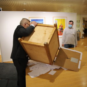 Rösträkning. En person tömmer rösterna från valurnan på ett bord.