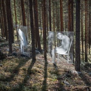 Läpikuultavia valkoisia hahmoja levyissä kiinnitettyinä puihin
