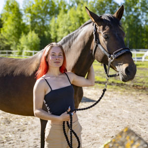 Kvinna med rött hår tillsammans med en häst.