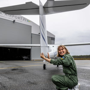 Kvinna i grön flygoverall inspekterar ultralätt flygplan