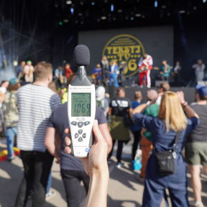 En decibelmätare mäter 106,0 decibel framför en festivalscen. 