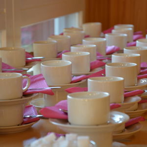 Flera kaffekoppar står uppradade med rosa servetter. 