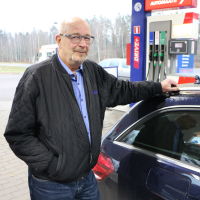 Skallig man med glasögon vid en bil.