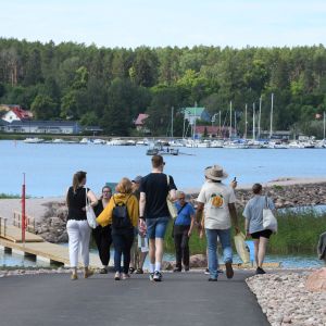 Besökare går ner för en backe med Lovisaviken i bakgrunden.