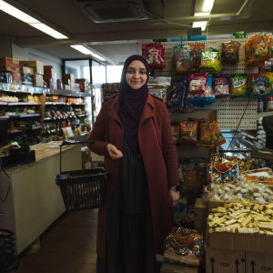 Porträttfoto av kvinna mellan hyllor i etnisk matbutik