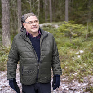 Man i skogen med grön jacka.