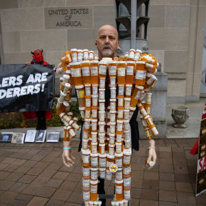 Frank Huntley, också känd som “Pill Man” står intäkt av sina egna pillerburkar i en protest mot familjen Sackler. Department of Justice building in Washington, D.C. on December 3, 2021