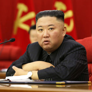 Kim Jong un sitter vid ett skrivbord. Framför honom en mikrofon.