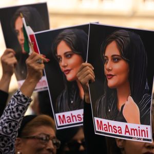 På bilden ses demonstranter som håller upp skyltar föreställande Mahsa Amini, en kvinna som dog efter att hon gripits av sedlighetspolisen i Iran.
