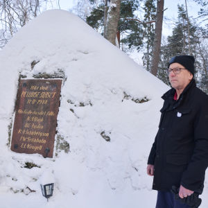 en fundersam erik liljeström framför den snötäckta minnesstenen över pellingeslaget