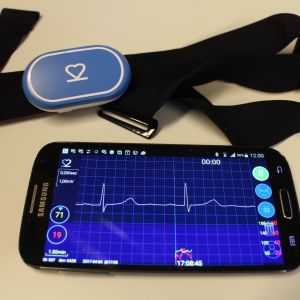 VTT:n kehittämä EKG-laite sykevyössä sekä älypuhelimen näytöllä sovelluksen välittämä kuva normaalista sydämen rytmistä. Valokuva Teija Peltoniemi.