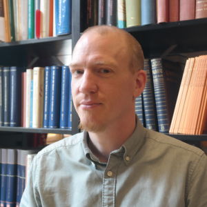 Universitetslärare Patrik Hagman framför en bokhylla