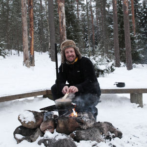 MIkko Peltola valmistaa ruokaa nuotiolla Nuuksiossa.