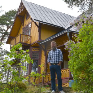 Berndt Arell framför Villa Ljungars. Här är villornas fasader vända mot farleden för att ge ett trevligt intryck vid inseglingen till Åbo. Berndt Arell vid några syrenbuskar framför det gula trähuset.