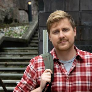 Staffan Gräsbeck prisar Mikael Grönroos mångsidighet. Staffan Gräsbeck med ryggsäck på ena axeln framför studiohuset i Böle 16.9. 2019..