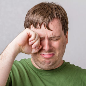 En man torkar tårar med handen från sina ögon.