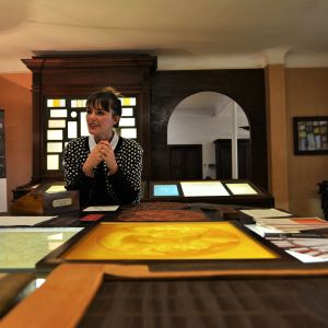 Livia Faggioni är samordnare för det historiska arkivet hos stiftelsen Fedrigoni i Fabriano. Här finns en unik samling maskiner och vattenmärken som idag är del av det italienska kulturarvet. En kvinna sitter bakom ett stort bord täckt av ramar och papper.
