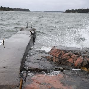 I framtiden kommer vintrarna att vara mer regniga och solen kommer att titta fram allt mer sällan, enligt Meteorologiska institutet. Vågor slår mot klippa på Drumsö i Helsingfors. Bilden är tagen vid en betongbrygga.