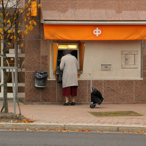 En kvinna tar ut pengar ur en bankomat.