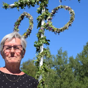 Kvinna står vid midsommarstång.