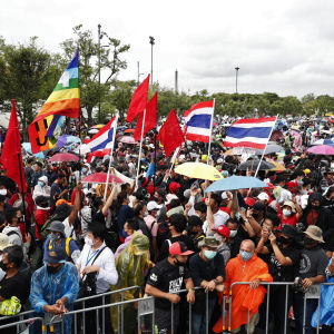 Det ruskiga vädret stoppar inte demonstranterna. Bild på folkmassa i Thailand. Personerna har paraplyn och regnjackor i muntra färger.