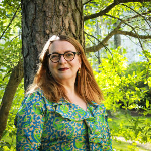 Litteraturvetaren, författaren Agneta Rahikainen i ett somrigt lövskogslandskap.