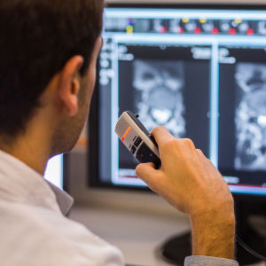 Läkare tittar på bilder från en MRI-undersökning och dikterar i en diktafon.