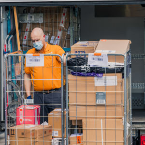 Kuorma-auton kuljettaja Joona Lyytikäinen ottaa autosta paketteja sisältäviä rullakoita.