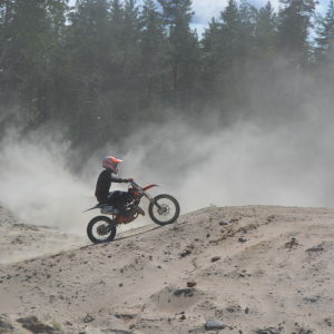 En motocrossförare åker på sand.
