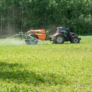 Traktori ruiskuttaa torjunta-aineita Etelä-Hämäläisellä pellolla