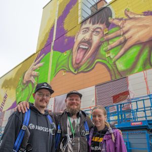 Kolme henkilöä Käärijä-muraalin edessä. 