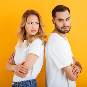 Ung man och kvinna står rygg mot rygg och blänger irriterat på varandra