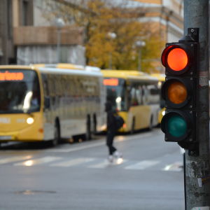 En buss står vid ett övergångsställe, ett rött trafikljus i förgrunden.
