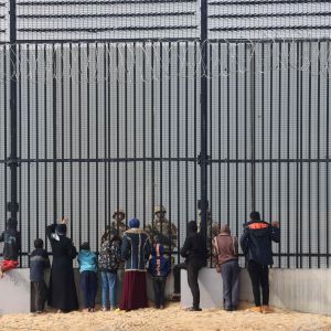 Palestinska flyktingar talar med egyptiska soldater vid ett gränsstaket.