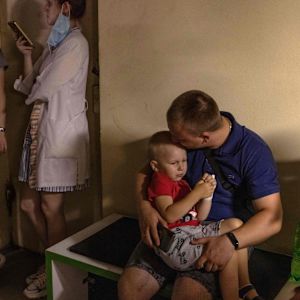 En ukrainsk pojke sitter i famnen på en man.