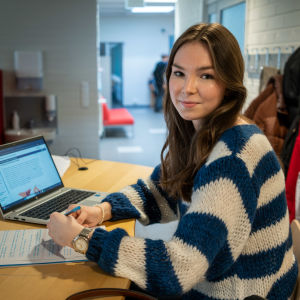 Porträttfoto av kvinna som arbetar på dator vid ett bord