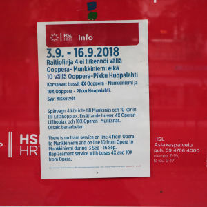 En lapp med information på finska, svenska och engelska på röd bakgrund.