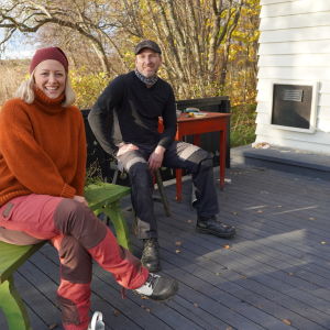 En man och en kvinna i medelåldern som sitter på en bänk och en pall på en svart altan.