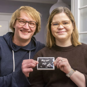 Sam och Julia Stenvall håller upp en ultraljudsbild på deras ofödda barn. 