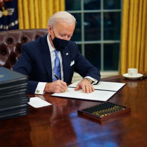 Joe Biden sitter vid skrivbordet i Ovala rummet och undertecknar dekret.
